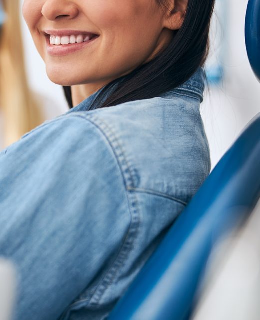 Positive delighted patient sitting in the cabinet of her stomatologist while doing checkup